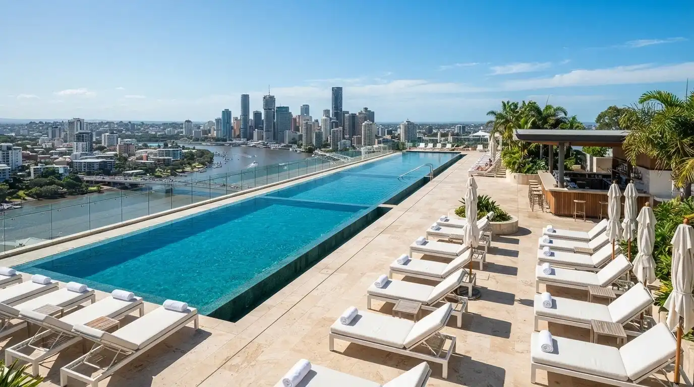 Three infinity-edge pools at Isoletto Pool Club, with sun lounges facing the Brisbane River and city skyline